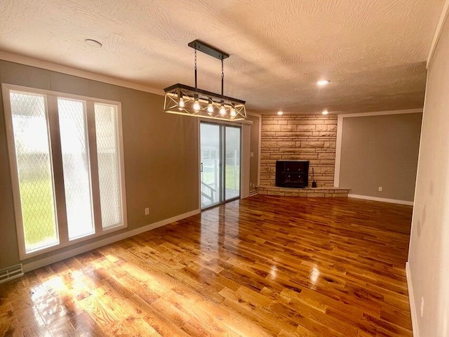 unfurnished living room featuring a fireplace, hardwood / wood-style floors, ornamental molding, and a textured ceiling