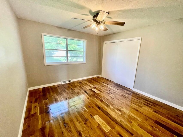 unfurnished bedroom with hardwood / wood-style flooring, ceiling fan, a textured ceiling, and a closet