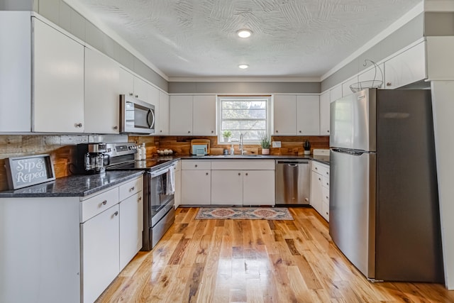 kitchen featuring white cabinets, stainless steel appliances, a textured ceiling, and light hardwood / wood-style flooring