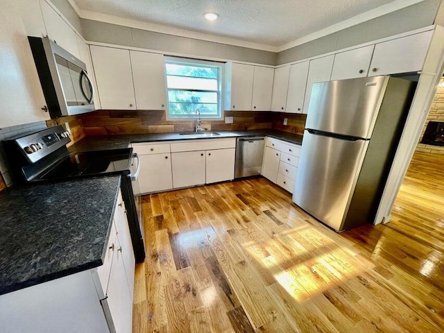 kitchen featuring white cabinetry, light wood-type flooring, stainless steel appliances, and a textured ceiling