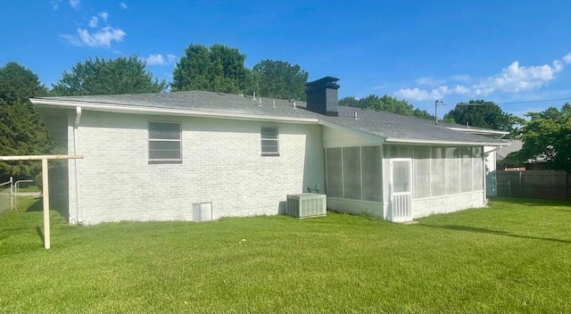 rear view of house with a sunroom, a yard, and central AC