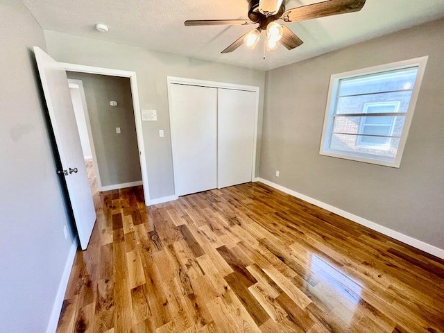 unfurnished bedroom with a closet, light wood-type flooring, and ceiling fan