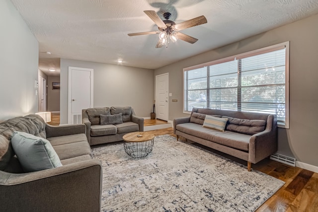 living room featuring hardwood / wood-style flooring, ceiling fan, and a textured ceiling