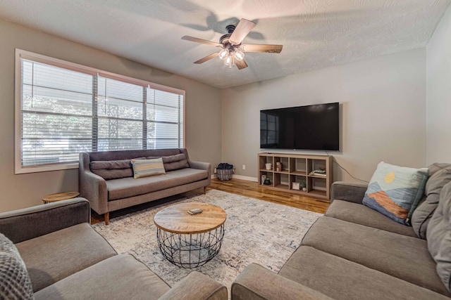 living room with a wealth of natural light, ceiling fan, a textured ceiling, and light wood-type flooring