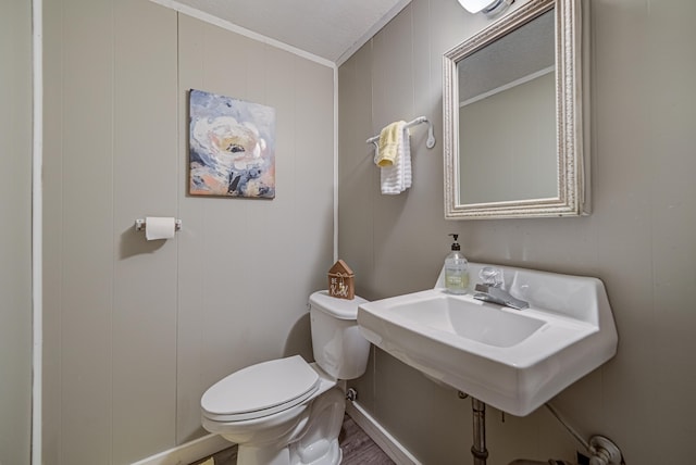 bathroom featuring toilet, wood-type flooring, and ornamental molding