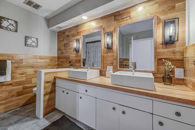 bathroom with vanity, wooden walls, and toilet