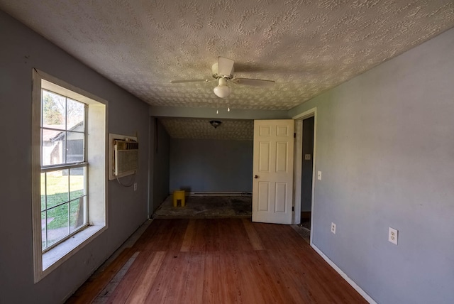 interior space featuring dark wood-type flooring, a wall unit AC, a textured ceiling, and ceiling fan