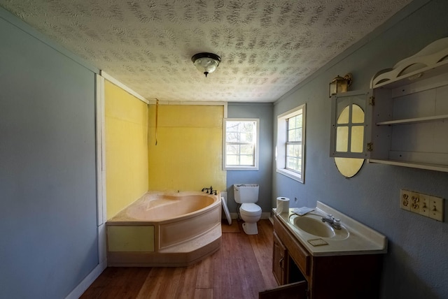 bathroom featuring hardwood / wood-style flooring, a textured ceiling, vanity, a bathing tub, and toilet