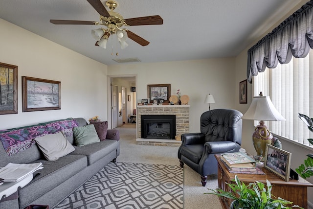 living room with a stone fireplace, ceiling fan, and light colored carpet