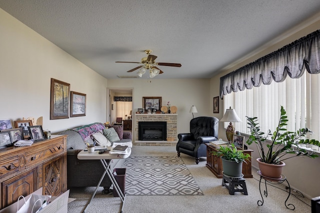 carpeted living room with a stone fireplace, ceiling fan, and a textured ceiling