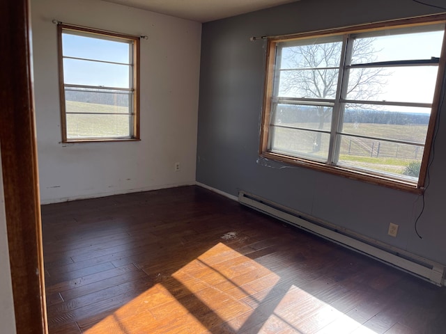 spare room featuring dark wood-type flooring and a baseboard radiator