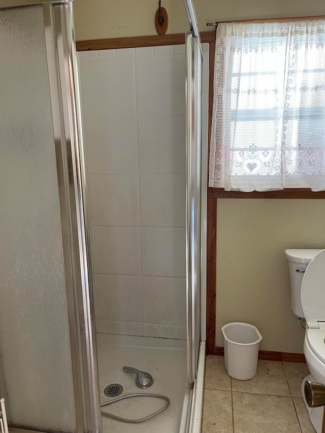 bathroom featuring toilet, tile patterned floors, and a shower with door