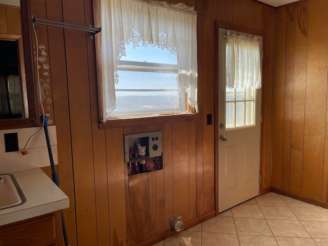 doorway to outside featuring light tile patterned flooring, wooden walls, and a healthy amount of sunlight