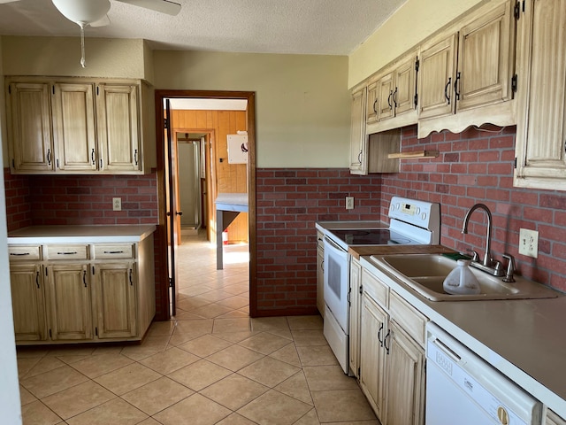 kitchen with white appliances, sink, light tile patterned flooring, and a textured ceiling