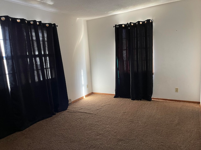 carpeted empty room featuring a textured ceiling