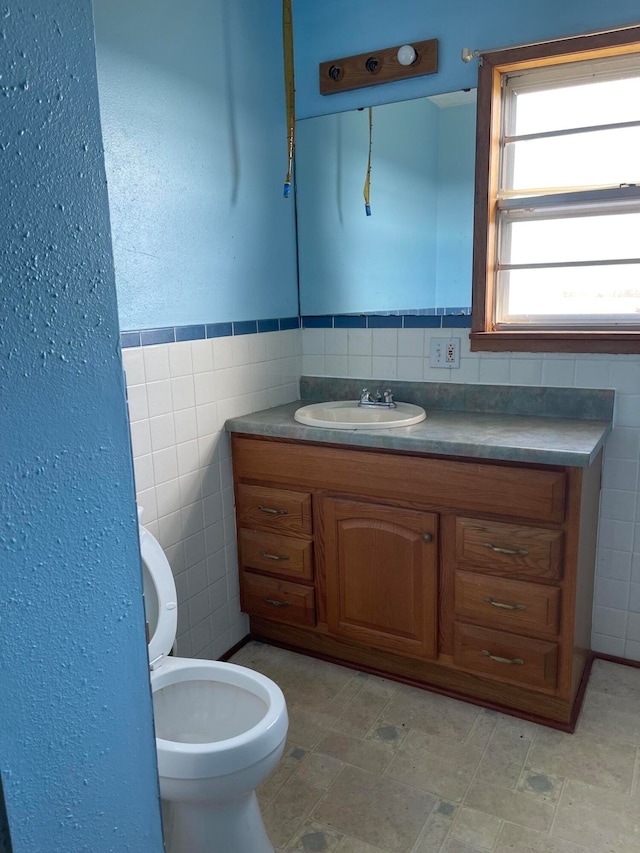 bathroom featuring vanity, toilet, and tile walls