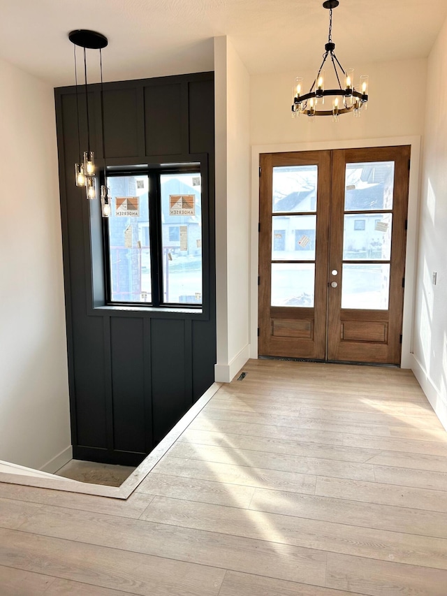 doorway to outside featuring a notable chandelier, light wood-type flooring, and french doors