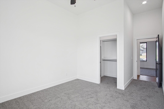 unfurnished bedroom featuring a closet, carpet floors, ceiling fan, and a spacious closet