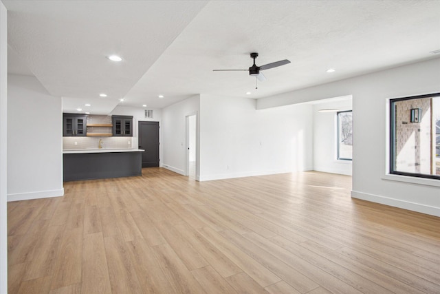 unfurnished living room with ceiling fan and light wood-type flooring