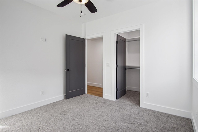 unfurnished bedroom with light carpet, a spacious closet, a closet, and ceiling fan