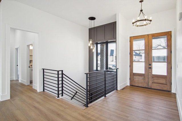 foyer entrance with an inviting chandelier, french doors, and light wood-type flooring