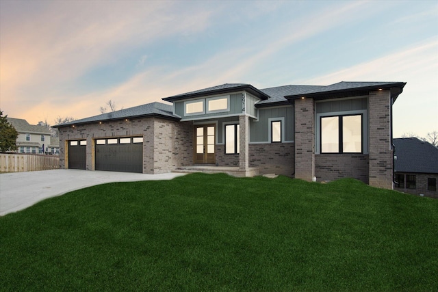 prairie-style home featuring a garage and a yard