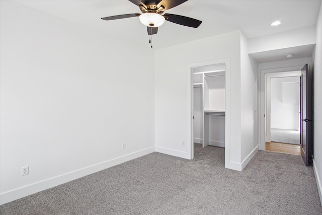 unfurnished bedroom with a walk in closet, light colored carpet, a closet, and ceiling fan