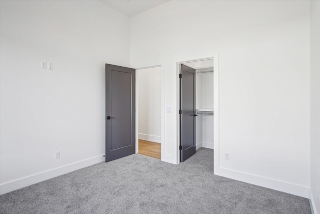 unfurnished bedroom featuring a walk in closet, carpet flooring, and a high ceiling