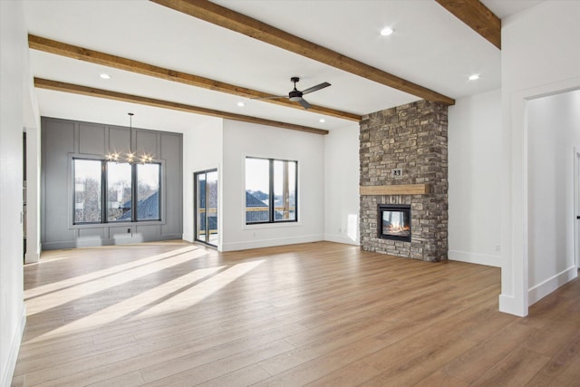 unfurnished living room with plenty of natural light, a fireplace, light hardwood / wood-style floors, and beam ceiling