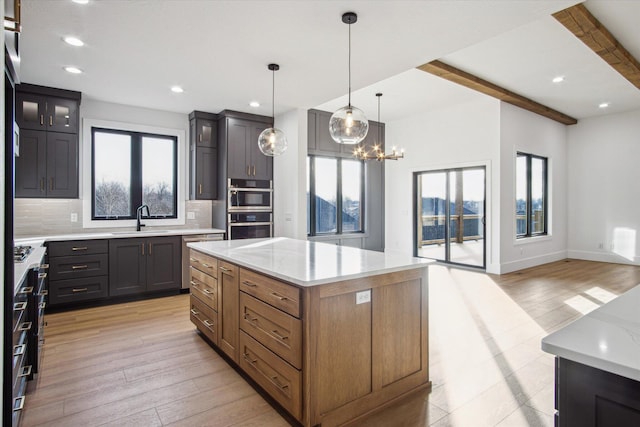 kitchen featuring sink, tasteful backsplash, hanging light fixtures, a kitchen island, and a wealth of natural light