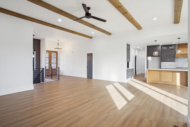 unfurnished living room with ceiling fan with notable chandelier, light hardwood / wood-style flooring, french doors, and beamed ceiling