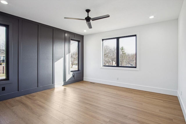 empty room with ceiling fan and light hardwood / wood-style flooring