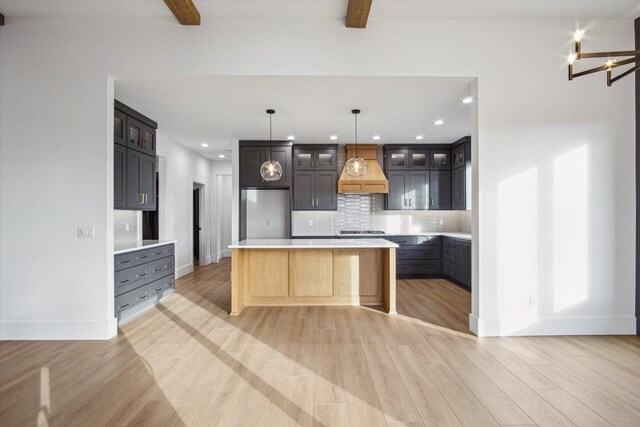 kitchen with tasteful backsplash, custom range hood, pendant lighting, and beamed ceiling