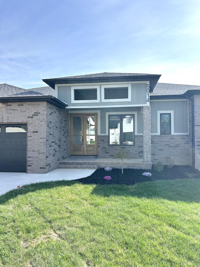 prairie-style house with brick siding, a garage, and a front lawn