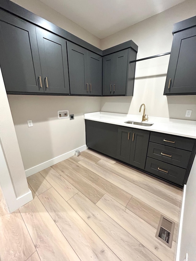 laundry area featuring cabinets, sink, hookup for a washing machine, light wood-type flooring, and hookup for an electric dryer