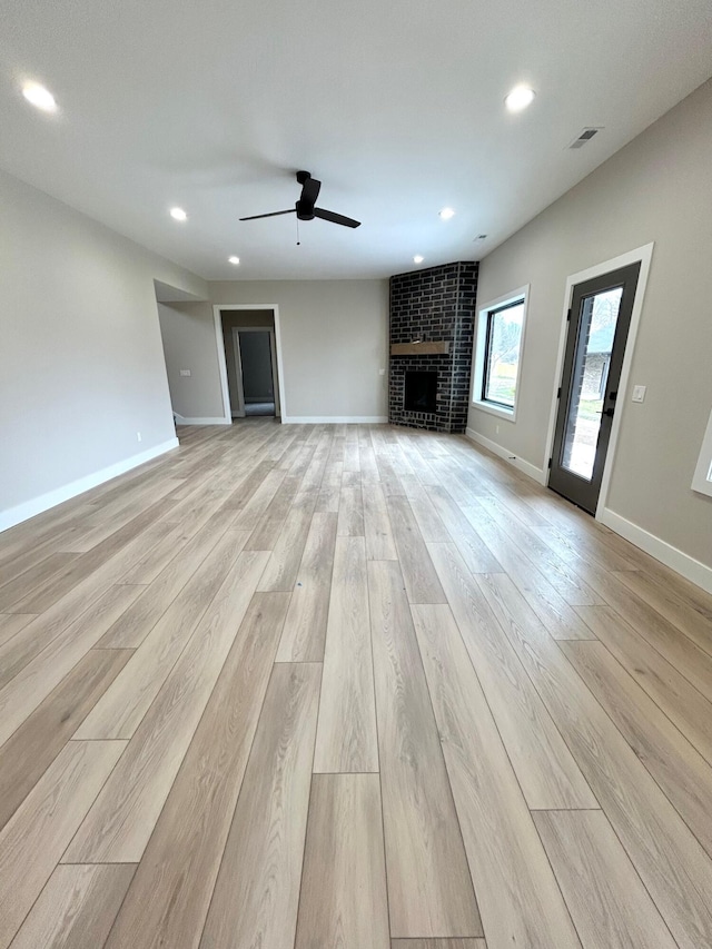 unfurnished living room featuring ceiling fan, light hardwood / wood-style floors, and a fireplace