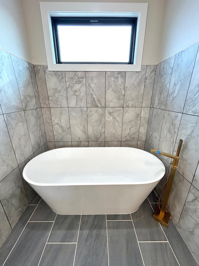 bathroom with tile patterned floors, a bathtub, and plenty of natural light