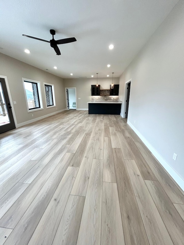 unfurnished living room with light hardwood / wood-style flooring and ceiling fan