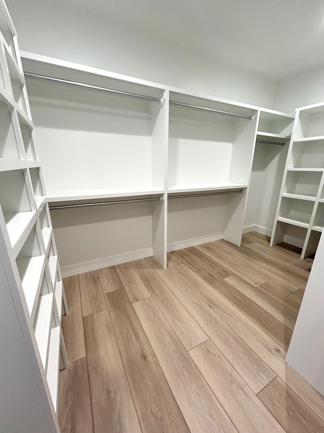 walk in closet with light hardwood / wood-style floors