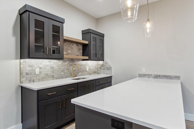 kitchen featuring a peninsula, tasteful backsplash, glass insert cabinets, a sink, and open shelves