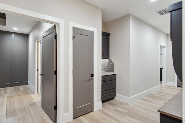 hallway with baseboards, light wood-style flooring, and visible vents