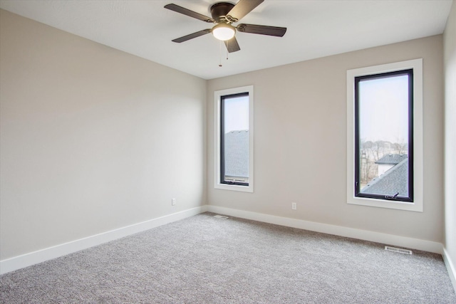 empty room with baseboards, carpet floors, ceiling fan, and visible vents