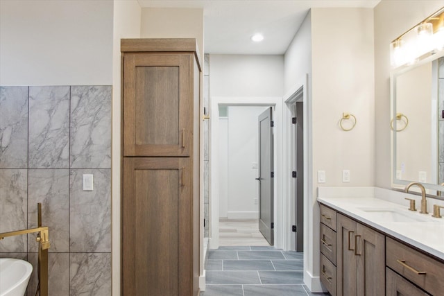 full bathroom featuring a soaking tub, vanity, and tile walls