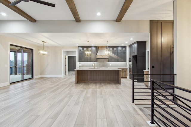 kitchen featuring light countertops, decorative backsplash, beam ceiling, light wood-style floors, and custom exhaust hood
