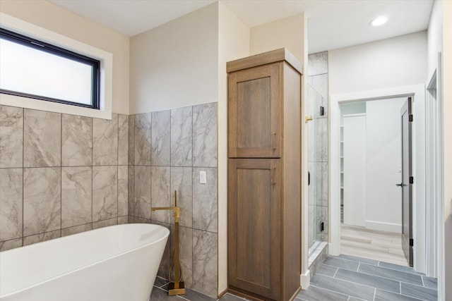 bathroom with tile walls, a stall shower, and a freestanding bath