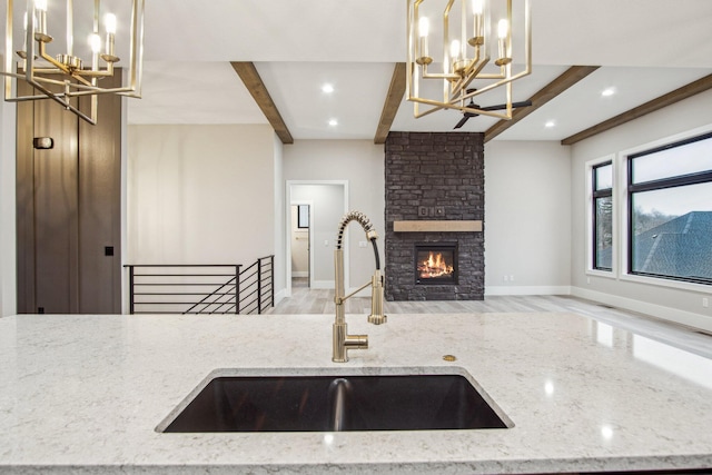 kitchen featuring an inviting chandelier, open floor plan, a sink, and beam ceiling