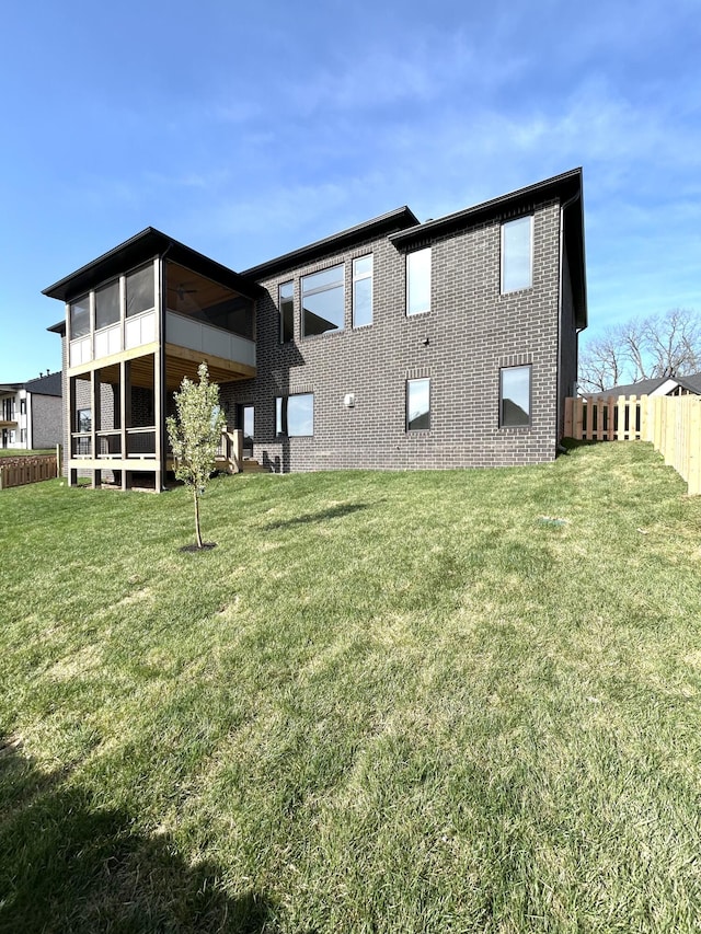back of house with a sunroom, fence, brick siding, and a yard