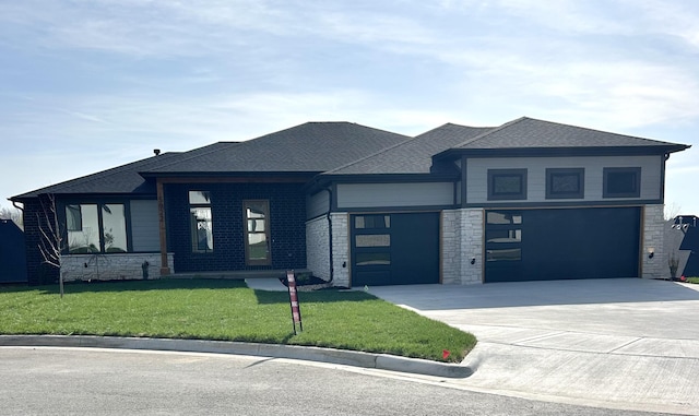 prairie-style house with roof with shingles, stone siding, driveway, a front yard, and a garage