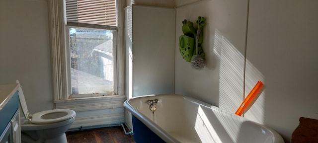 bathroom with a washtub, hardwood / wood-style floors, and toilet