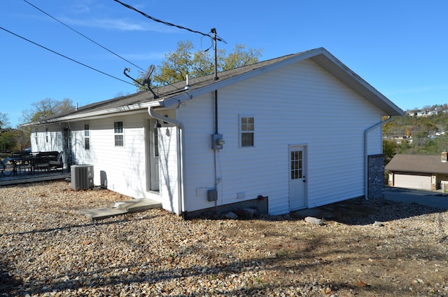 rear view of property with central AC unit and a garage